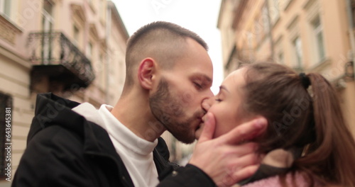 Close-up of the faces of a young couple in love kissing and hugging on the street on a gloomy autumn day.