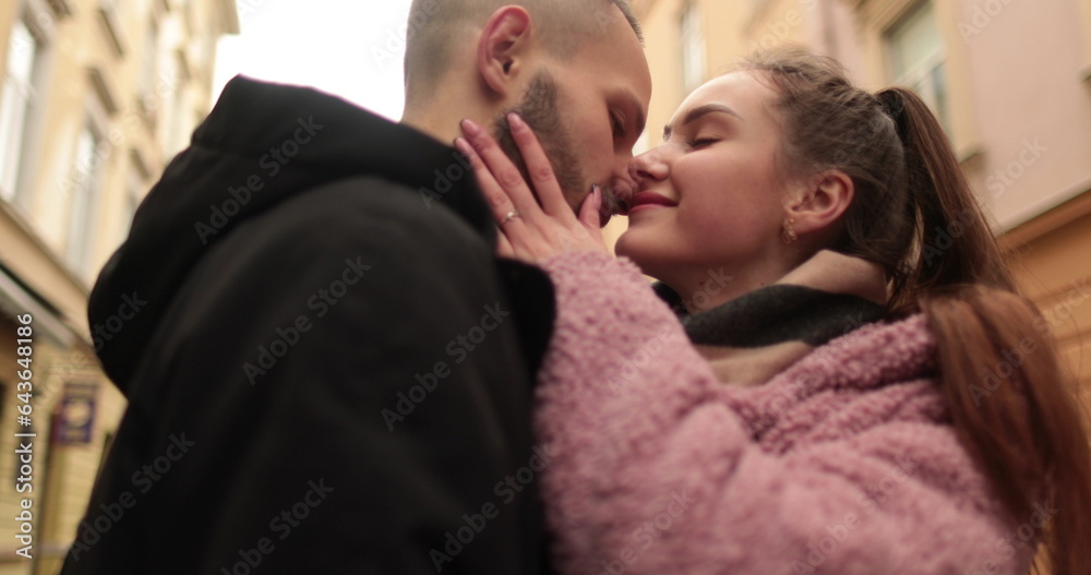 Close-up of the faces of a young couple in love kissing and hugging on the street on a gloomy autumn day. Close-up of the faces of a young couple in love kissing and hugging on the street on a gloomy autumn day.