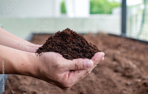 Hand holding fertile black soil. Agriculture, organic gardening, planting or ecology concept. Environmental, earth day. Banner. Top view. Copy space. Farmer checking before sowing