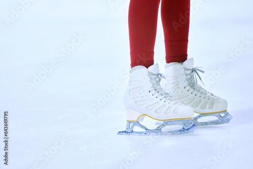 Close-up cropped image of female legs in red leggings and white skates on ice skate arena. Training and skating. Concept of professional sport, competition, sport school, health, hobby, ad