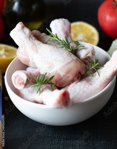 Raw chicken legs on slate plate. on wooden background. closeup