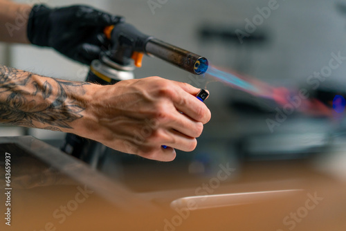 Close-up of chef's hand with gas burner and lighter before frying food in professional kitchen