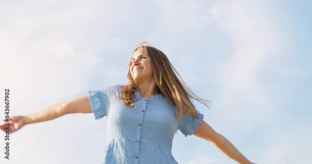 Woman rising hands feeling free, relaxing, spinning against sky background
