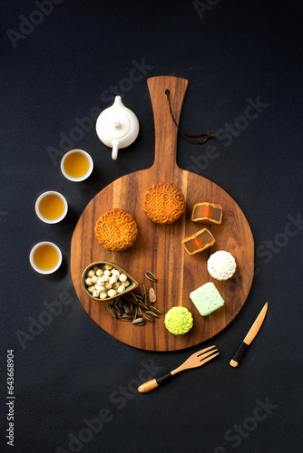 Flat lay Mid-autumn festival food and drinks - mooncake and tea set on black background. photo