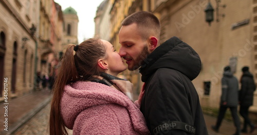 Kisses and hugs of a young couple in love. A romantic meeting of a young couple in the city center on a gloomy autumn day. Happy boy and girl hug, kiss, enjoying time together.