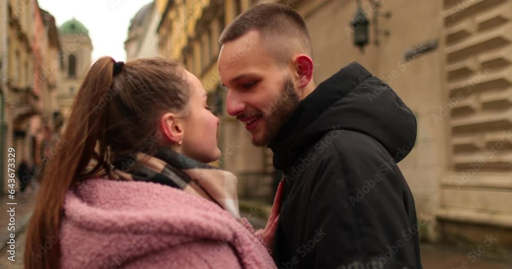 Kisses and hugs of a young couple in love. A romantic meeting of a young couple in the city center on a gloomy autumn day. Happy boy and girl hug, kiss, enjoying time together. Kisses and hugs of a young couple in love. A romantic meeting of a young couple in the city center on a gloomy autumn day. Happy boy and girl hug, kiss, enjoying time together.