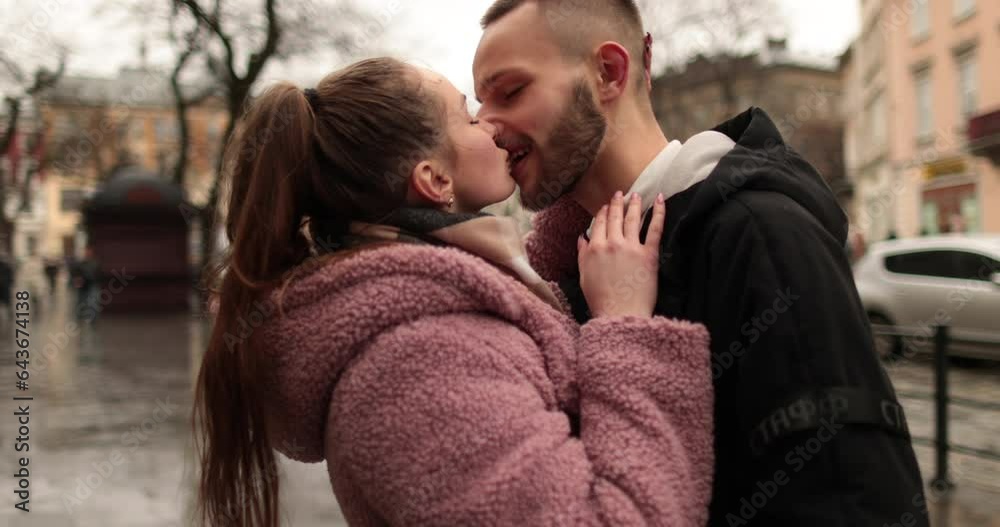 Kisses and hugs of a young couple in love. A romantic meeting of a young couple in the city center on a gloomy autumn day. Happy boy and girl hug, kiss, enjoying time together. Kisses and hugs of a young couple in love. A romantic meeting of a young couple in the city center on a gloomy autumn day. Happy boy and girl hug, kiss, enjoying time together.