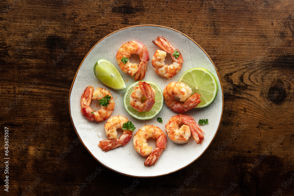 Shrimps, overhead flat lay shot. Fried shrimp with lime on a white plate, shot from the top on a rustic wooden background. Gourmet dish Shrimps, overhead flat lay shot. Fried shrimp with lime on a white plate, shot from the top on a rustic wooden background. Gourmet dish