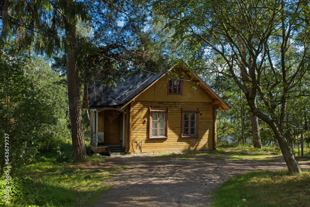 Small wooden yellow hut inside a forest park in summer on the island of Seurasaari, Helsinki, Finland. Small wooden yellow hut inside a forest park in summer on the island of Seurasaari, Helsinki, Finland.