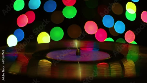 Turntable against the background of multi-colored spots in the dark, close-up

