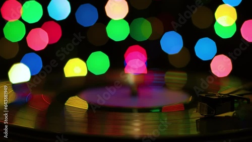 Turntable against the background of multi-colored spots in the dark, close-up
