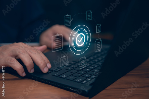 Businessman using laptop with document icon and correct mark for standard quality control certification concept.
