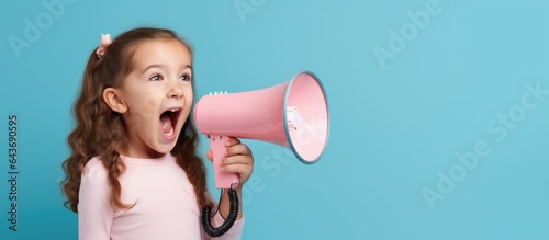 Caucasian child in pink T shirt over blue background expressing genuine emotions representing lifestyle concept through a megaphone