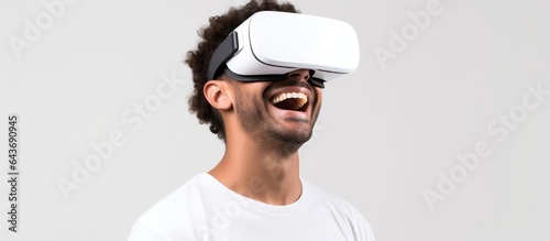 An African American man wearing a white t shirt and virtual reality glasses happily gazes at empty space while being isolated on a white background
