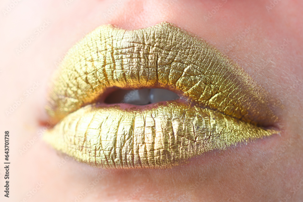 Fototapeta premium Close up female plump lips with gold. Golden glitter lipstick. Shine style for sexy lip. Sensual woman lips. Luxury golden mouth. Glamour gold lips. Golden lips with golden paint or metallic lipstick.