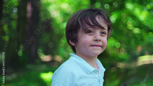 Bright Day Park Portrait/ Little Boy Faces Camera Amidst Lush Greenery