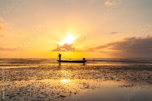 A fishing man on the boat in stunning yellow sunrise at Talay Noi lagoon..In the morning, fishermen go out to find fish in the sea at Khlong Pak Pra, .Thale Noi, Phatthalung Province.