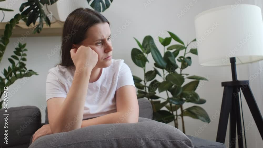 Unhappy young woman 25s sitting on couch with sad expression face thinking about problem, difficulty, feeling failure and exhausted, suffering from loneliness, grief sorrow and bad relationship Unhappy young woman 25s sitting on couch with sad expression face thinking about problem, difficulty, feeling failure and exhausted, suffering from loneliness, grief sorrow and bad relationship
