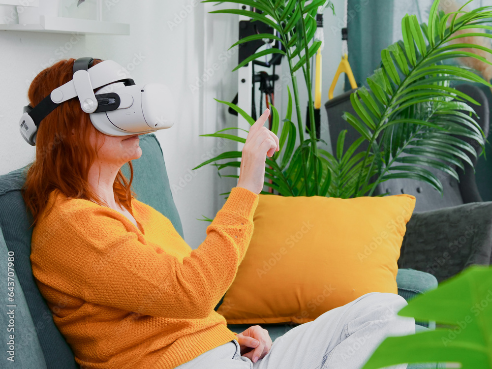 woman sitting on sofa relaxing and playing VR and using futuristic artificial intelligence at home.. the concept of metaverse, virtual reality, future, technology, and internet of things.