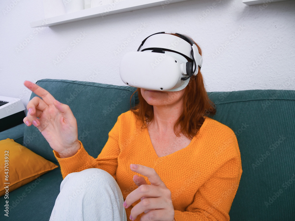 woman sitting on sofa relaxing and playing VR and using futuristic artificial intelligence at home.. the concept of metaverse, virtual reality, future, technology, and internet of things.