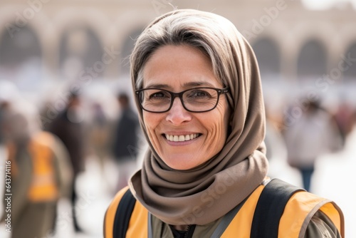 Headshot portrait photography of a cheerful mature woman wearing a thermal insulation vest at the mecca in saudi arabia. With generative AI technology