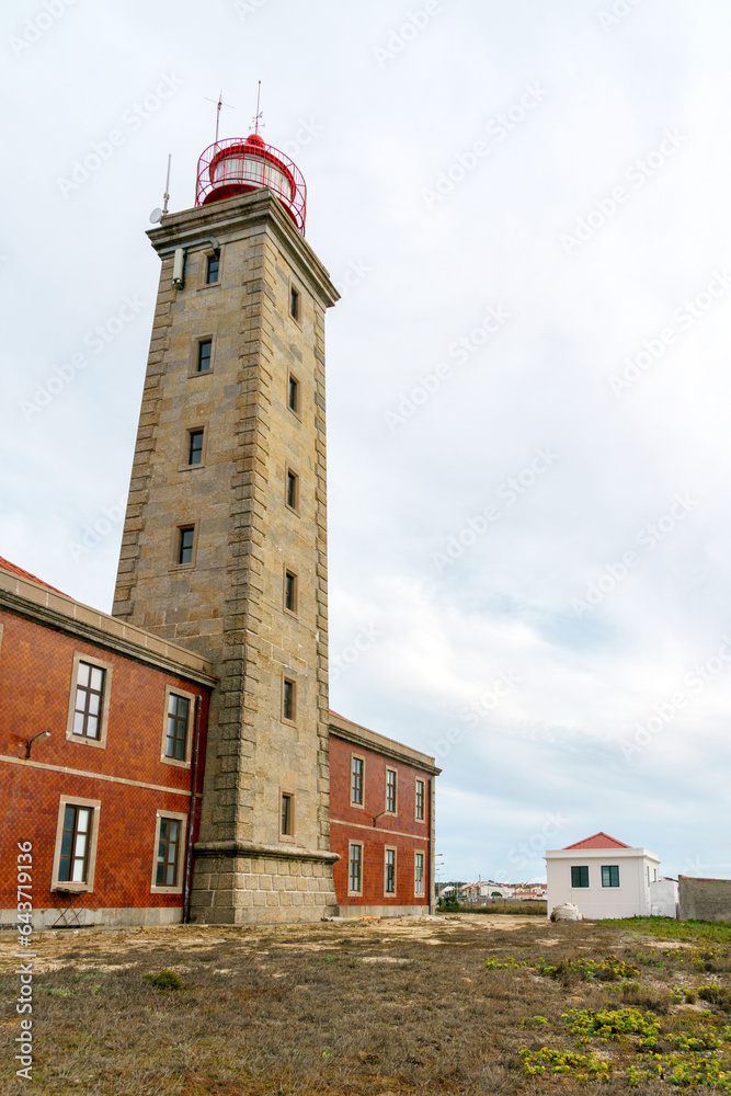tall old lighthouse building against a grey blue clouded sky