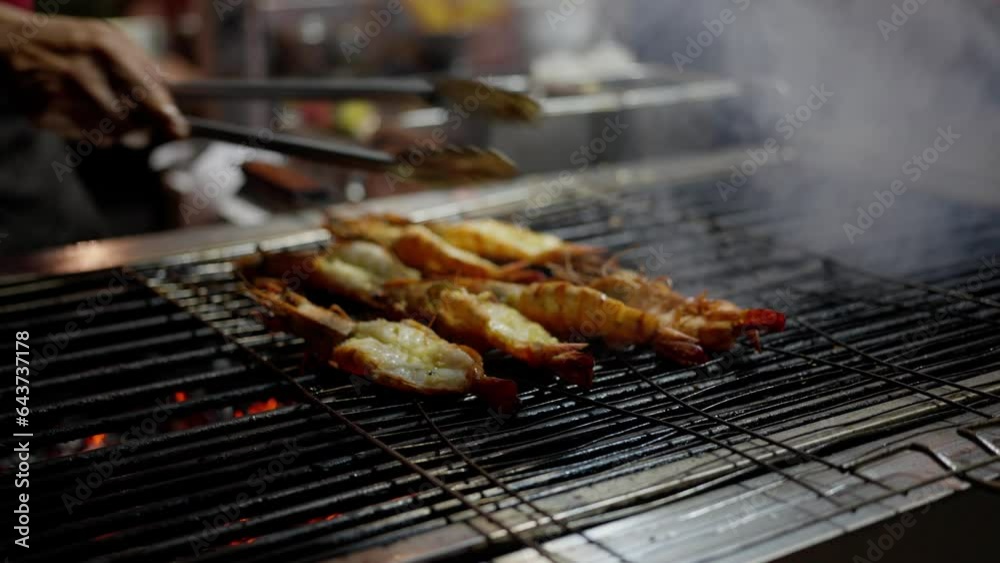 Shelled prawns turning on a skewer above an open flame, A man flips shrimp on the grill, seafood on fire. Shelled prawns turning on a skewer above an open flame, A man flips shrimp on the grill, seafood on fire.