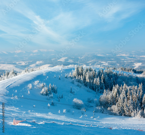 Morning winter calm mountain landscape with beautiful frosting trees in mountains shadows and ski slope (Carpathian Mountains, Ukraine)
