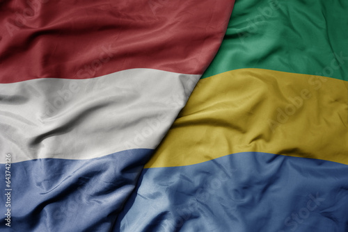 big waving national colorful flag of netherlands and national flag of gabon .