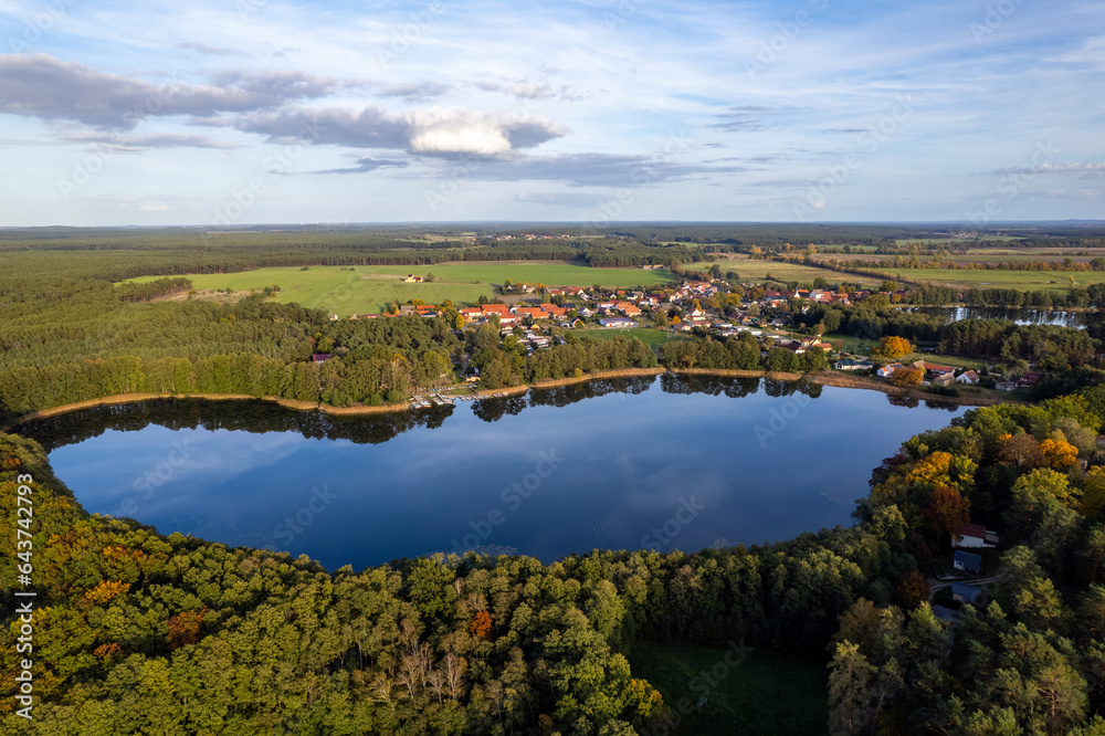Aerial shot of beautiful lake surrounded by forest in a calm autumn day. Germany. 4K video.