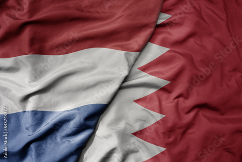 big waving national colorful flag of netherlands and national flag of bahrain .