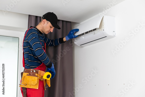 Male technician fixing air conditioner indoors.