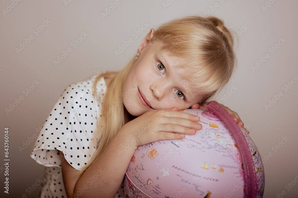 The girl hugs the globe. Back to school soon. For the first time in first class. The girl hugs the globe. Back to school soon. For the first time in first class.