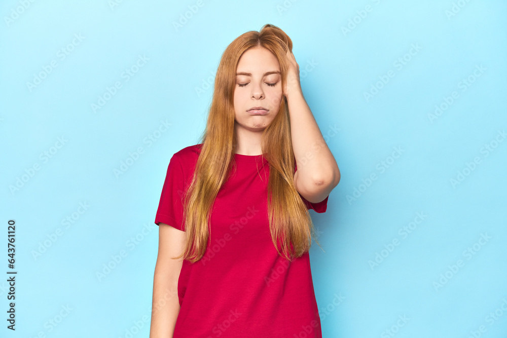 Redhead young woman on blue background tired and very sleepy keeping hand on head. Redhead young woman on blue background tired and very sleepy keeping hand on head.