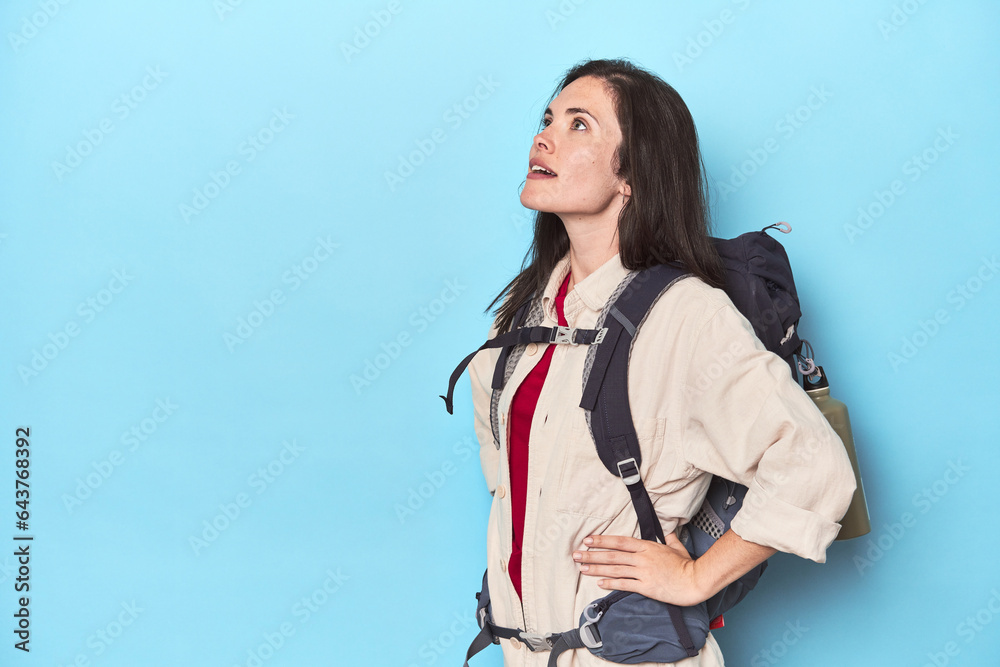 Adventurous woman with backpack and mat on blue Adventurous woman with backpack and mat on blue