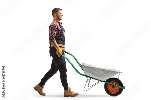 Foto Full length profile shot of a gardener pushing an empty wheelbarrow