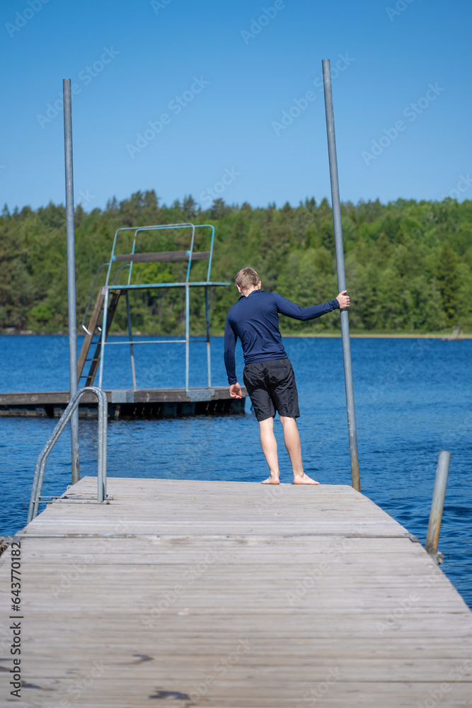 Young man stading on a pier about to jump in the water.