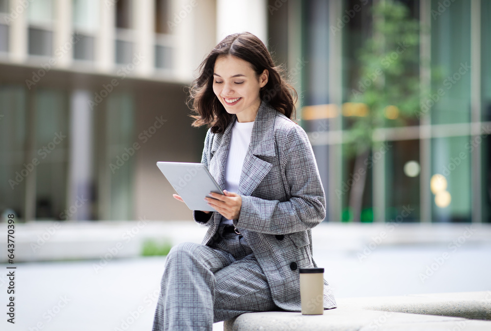 Happy young business woman typing on tablet near office building Happy young business woman typing on tablet near office building