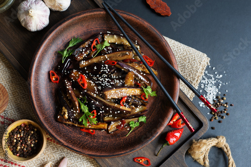 Chinese eggplant in sweet and sour sauce on a dark plate. food background