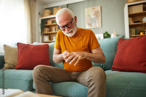 A senior man is experiencing everyday chronic pain in his fingers photo