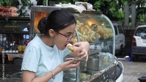 Happy Indian woman having North Indian subcontinent popular street food. Hand cracking panipuri. Street food. Appetizer.