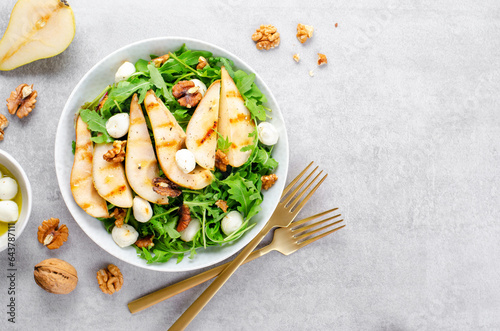 Grilled Pear Salad, Salad with Pear, Arugula, Mozzarella Pearls, Walnuts and Dressing over Bright Background