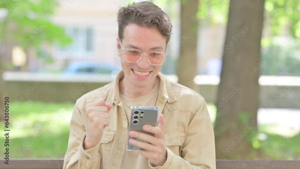 Casual Young Man Celebrating Win on Smartphone Outdoor Casual Young Man Celebrating Win on Smartphone Outdoor