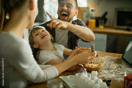 Young family baking together and having fun while being messy in the kitchen