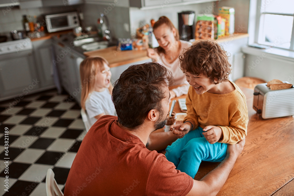 Young family having breakfast together and being messy in the kitchen Young family having breakfast together and being messy in the kitchen