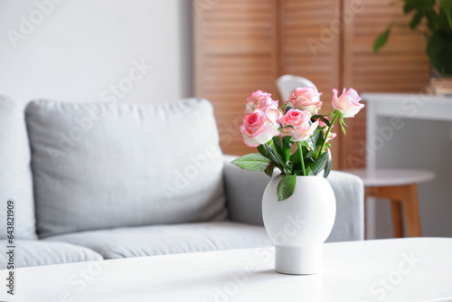 Vase with roses on table in living room, closeup
