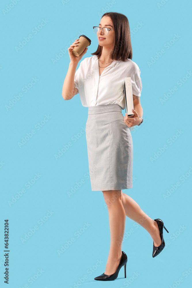 Young businesswoman with folder and cup of coffee on blue background Young businesswoman with folder and cup of coffee on blue background
