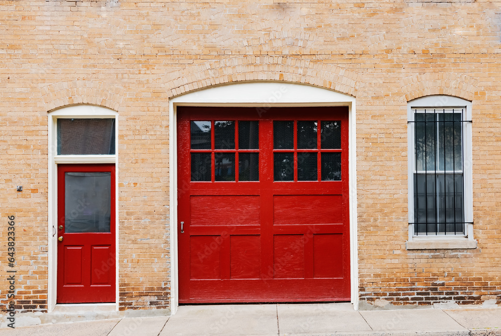 Wooden red front door and red gate to a brick house.