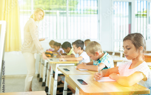 Portrait of focused tween schoolgirl writing exercises in workbook in classroom during lesson © JackF