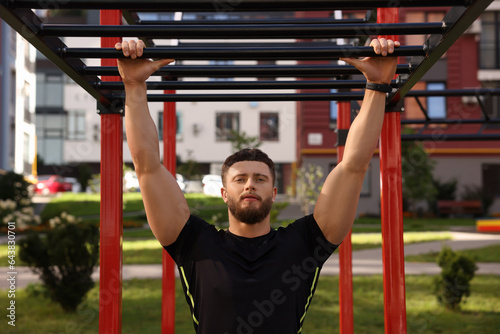 Man training on monkey bars at outdoor gym